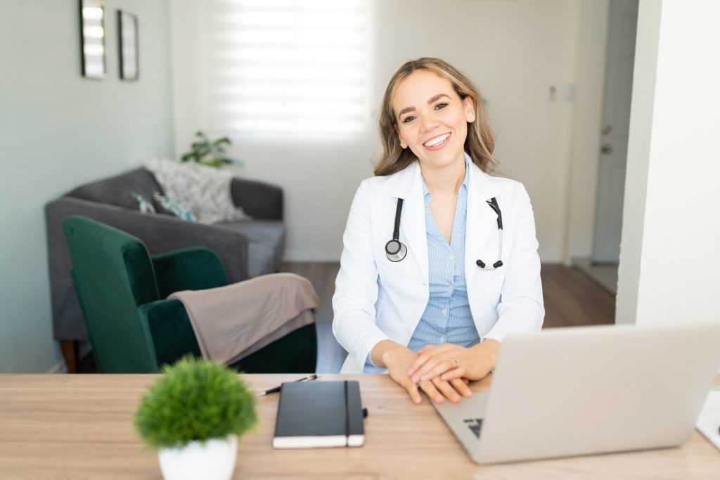 Friendly female doctor sitting in front of laptop