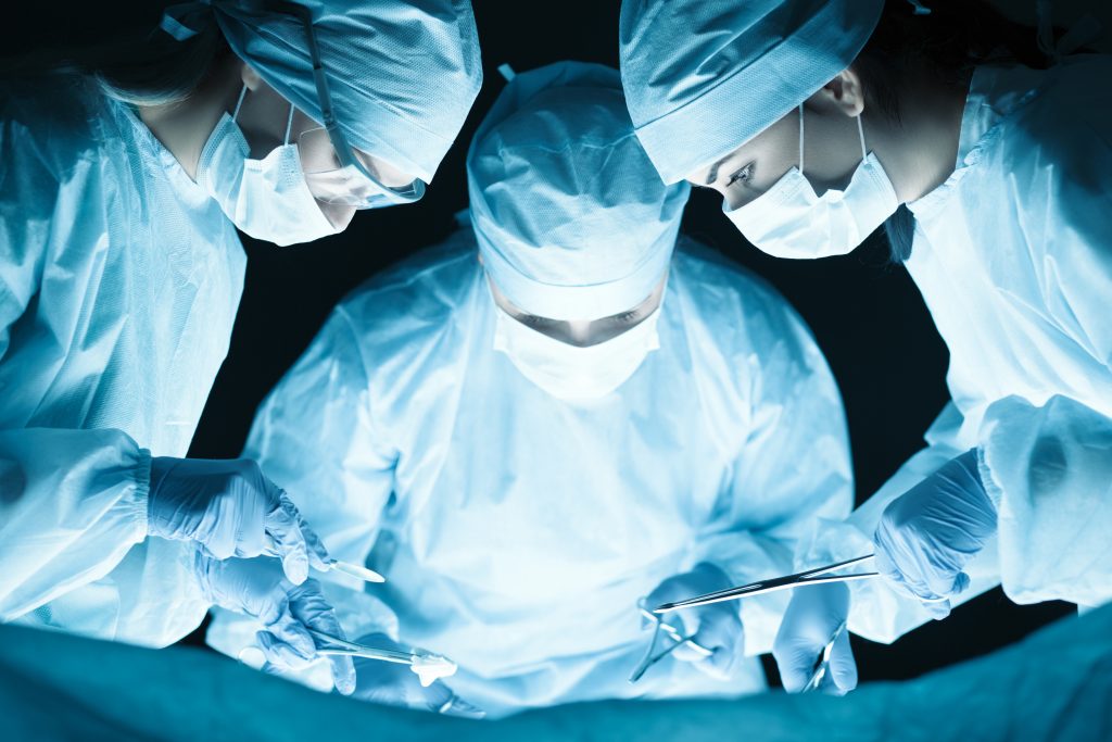Medical team performing operation. Group of surgeon at work in operating theatre tonned in blue