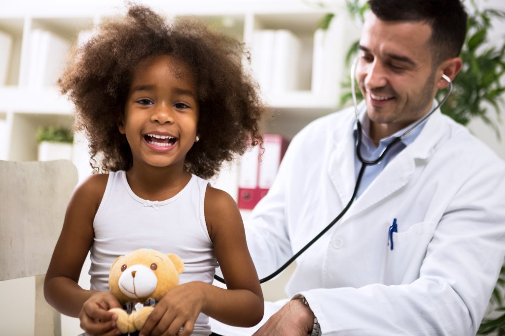 Pediatrician doctor examining happy smiling kid